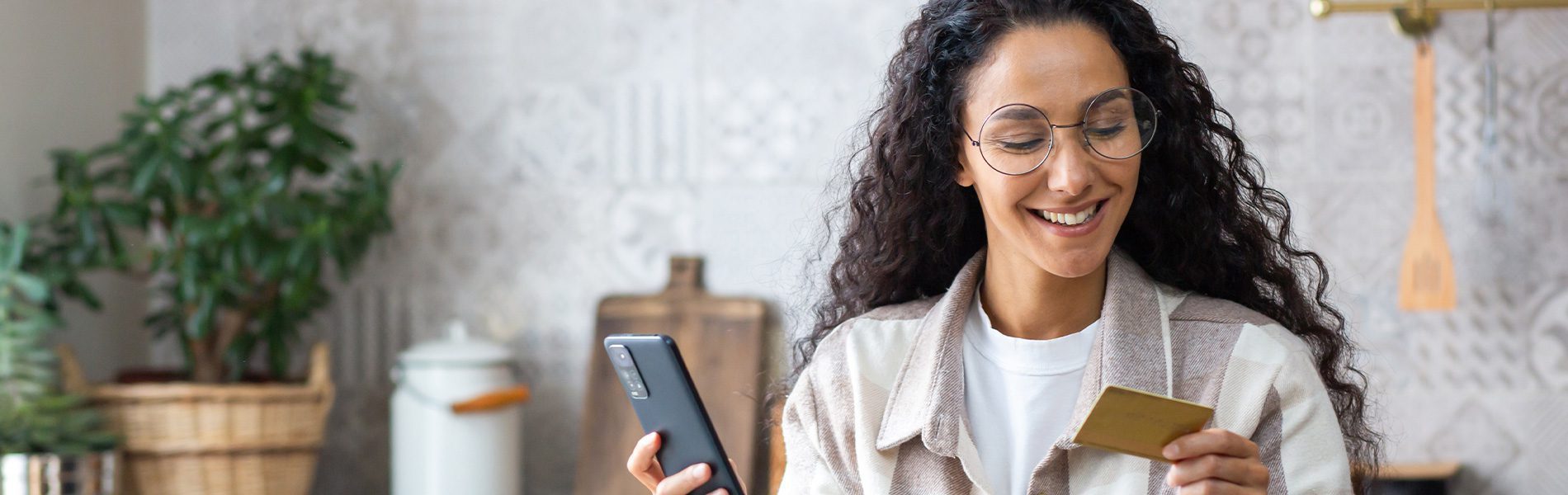 Frau hält Smartphone und Prepaid-Karte – Online-Bezahlung, geeignet für Gutscheine und Onlinedienste.