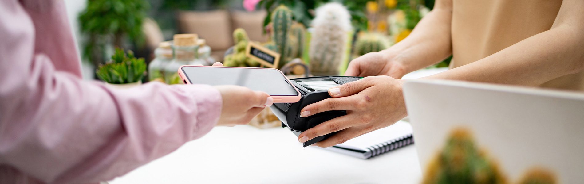 Smartphone wird an mobiles EC-Terminal gehalten – kontaktloses Bezahlen im Laden mit Kombi-Terminal.